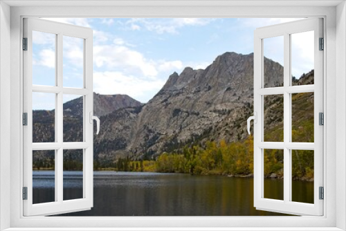 Fototapeta Naklejka Na Ścianę Okno 3D - Driving through June Lake loop in the Eastern Sierra, where towering mountains loom overhead and fall colors begin to show on some of the trees at their base. Seen here is Grant Lake.