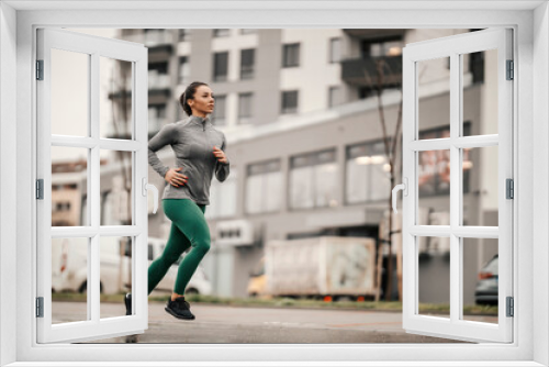 A fast urban female runner is running on the rainy day downtown.
