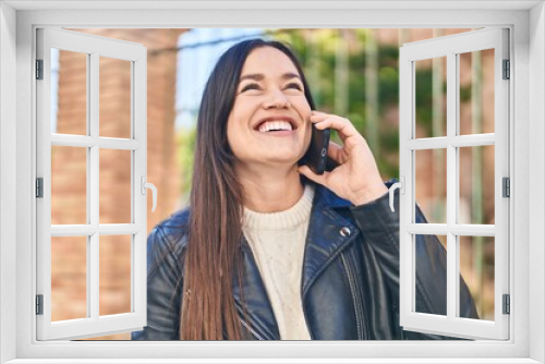 Young woman smiling confident talking on the smartphone at street