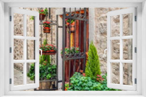 Fototapeta Naklejka Na Ścianę Okno 3D - Flower vases decorate the entrance to an old stone building in the Old Town of Budva, Montenegro. Vertical view of flower pots at the door in Stari Grad