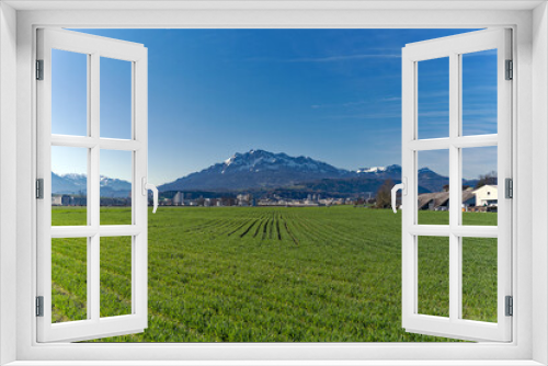 Fototapeta Naklejka Na Ścianę Okno 3D - Scenic landscape and Swiss Alps with agriculture field and mount Pilatus seen from City of Emmen, Canton Lucerne, on a sunny spring day. Photo taken March 22nd, 2023, Emmen, Switzerland.