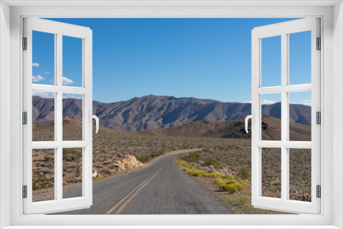 Fototapeta Naklejka Na Ścianę Okno 3D - Endless road stretching straight through Death Valley National Park, California, USA. Highway in dry Mojave desert on sunny summer day with Amargosa Mountain Range in back. Freedom road trip concept