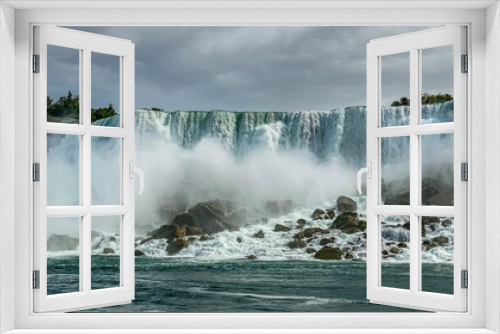 Fototapeta Naklejka Na Ścianę Okno 3D - Niagara falls and water mist, and the rocky coast of the Niagara River, on a cloudy day