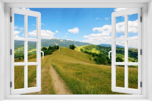 Fototapeta Naklejka Na Ścianę Okno 3D - country road down the hills and meadows rolling in to the distant valley. mountainous countryside landscape of ukrainian carpathians in summer