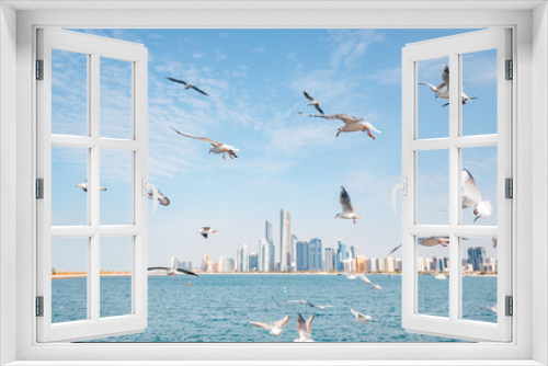 Fototapeta Naklejka Na Ścianę Okno 3D - Marvel at the towering skyscrapers of Abu Dhabi, and flock of seagulls flying by