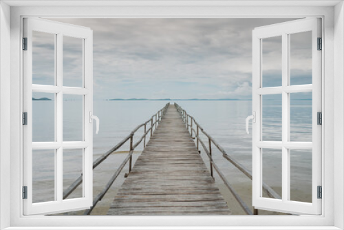 Fototapeta Naklejka Na Ścianę Okno 3D - Picturesque scenery of empty wooden pier placed on rippling sea under cloudy sky