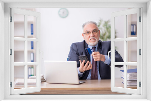 Old male employee holding credit card