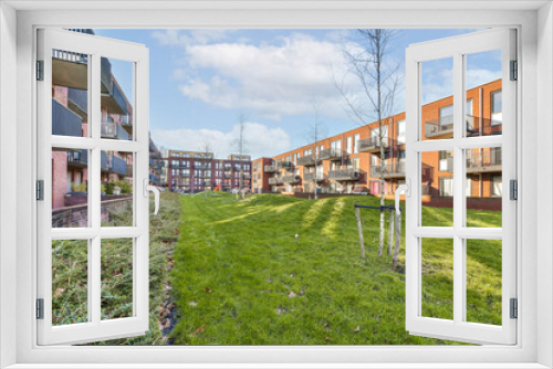 Fototapeta Naklejka Na Ścianę Okno 3D - an apartment complex with green grass and trees in the foreground area on a bright sunny day photo crediton / shutterstocker