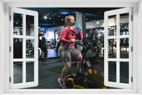 Beautiful, overweight woman push her limits during a workout, She exercises on stationary bike at the gym.