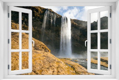 Fototapeta Naklejka Na Ścianę Okno 3D - The sight of the waterfall against the backdrop of the Icelandic landscape is breathtaking and makes for an unforgettable photo opportunity. Seljalandsfoss is a stunning waterfall located in Iceland