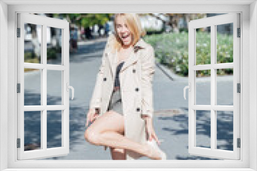 blonde fashionable woman in a raincoat on the street walk