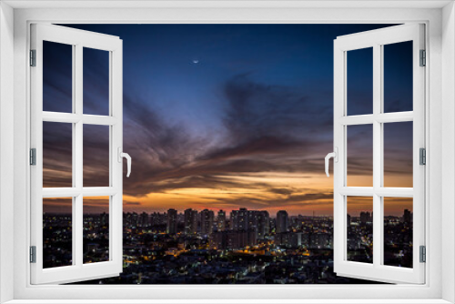 Fototapeta Naklejka Na Ścianę Okno 3D - Sunset seen from above the building with orange and blue colored sky with the moon in the center and avenues and buildings highlighted. | Avenida Ayrton Senna em Natal, RN.
