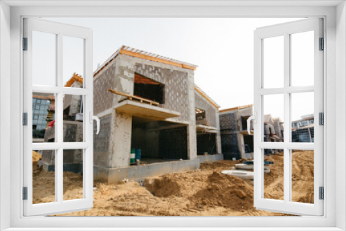 Fototapeta Naklejka Na Ścianę Okno 3D - construction of private modern cottages from blocks and cement against the blue sky