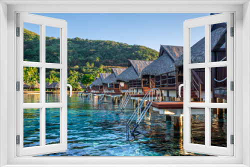 Fototapeta Naklejka Na Ścianę Okno 3D - Bungalow sur l'eau en Polynésie française avec une eau turquoise et du corails. Lieu de tourisme paradisiaque.