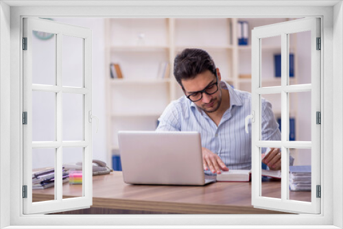 Young male employee reading book in the office