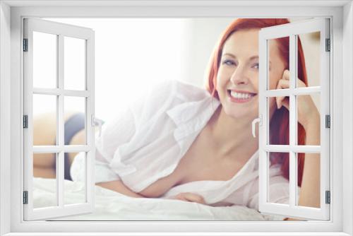 Portrait of beautiful redhead lying alone on a bed at home. One model feeling flirty and sexy while posing seductively in a bedroom on the weekend. Young woman wearing underwear and feeling sensual