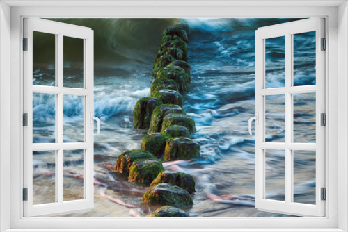 Fototapeta Naklejka Na Ścianę Okno 3D - Poruszona woda morska. Falochron porośnięty porostami w morskich falach wieczorem. Zielone glony. 