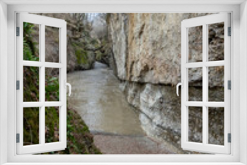 Fototapeta Naklejka Na Ścianę Okno 3D - Canyon of a mountain river during the melting of snow, a rapid stream of dirty water rushes to the plain.