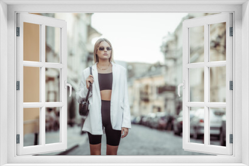 Young stylish blonde woman in trendy outfit on a European street. Street fashion