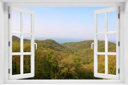 View of the green hills and trees on the sea coast.