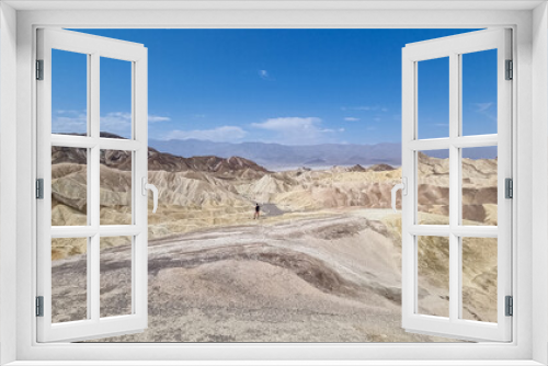 Fototapeta Naklejka Na Ścianę Okno 3D - Man with scenic view Badlands of Zabriskie Point, Furnace creek, Death Valley National Park, California, USA. Erosional landscape of multi hued Amargosa Chaos rock formations, Panamint Range in back