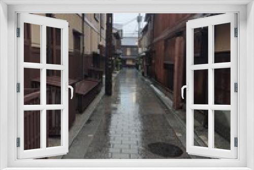 Fototapeta Naklejka Na Ścianę Okno 3D - L'insolite et touristique quartier de Gion, avec des petites ruelles à l'asiatique, de l'ancien Japon, sous un temps de pluie, avec ciel nuageux, des gens se promenant avec des parapluies