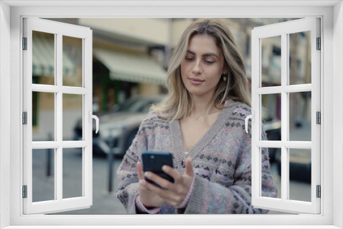 Young blonde woman using smartphone with relaxed expression at street