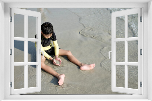 Fototapeta Naklejka Na Ścianę Okno 3D - Asian boy playing with sand at the beach in summer