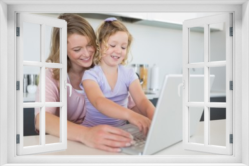 Mother assisting daughter in using laptop at table