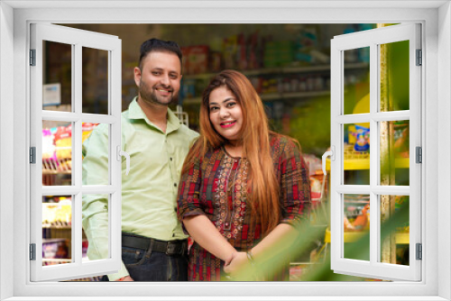 Happy Indian couple standing at grocery shop.