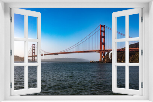 Fototapeta Naklejka Na Ścianę Okno 3D - The Golden Gate Bridge in San Francisco over the bay of the Californian city under a blue sky and ocean. Famous bridge in the state of California and seen from a viewpoint. Concept USA.