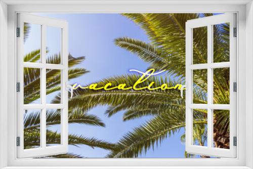 Fototapeta Naklejka Na Ścianę Okno 3D - Palm trees against blue sky at tropical coast. Sunleak texture. Vacation is written by yellow in the center of poster. Coconut tree, summer palm leaves.