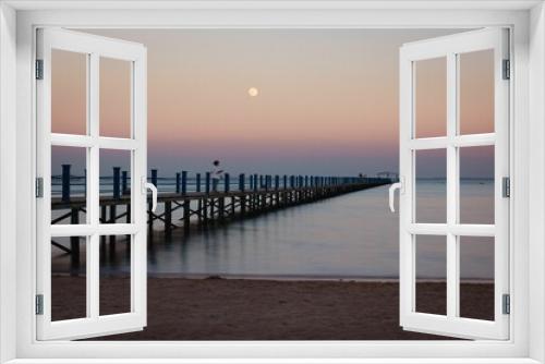 Fototapeta Naklejka Na Ścianę Okno 3D - Calm sea and wooden dock against the pink sunset sky with a full moon
