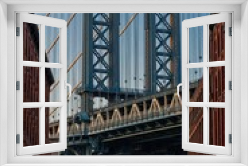Fototapeta Naklejka Na Ścianę Okno 3D - Vertical shot of the Brooklyn bridge seen through buildings in New York, U.S.