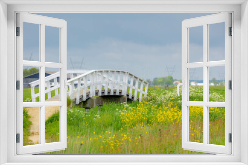 Fototapeta Naklejka Na Ścianę Okno 3D - Spring countryside landscape, Flat, low and water land, Typical Dutch polder with green meadow, White wooden bridge, Small canal or ditch and the grass field along the road, North Holland, Netherlands