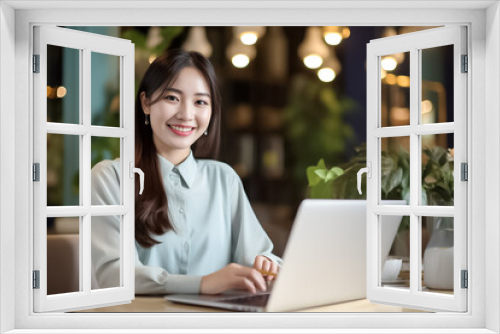 A happy Asian office girl working on her laptop in a cozy cafe, with a blurred background adding to the serene atmosphere. generative Ai.