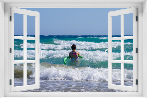 Fototapeta Naklejka Na Ścianę Okno 3D - Girl swims with green foam swimming tube near beach of wavy mediterranean sea