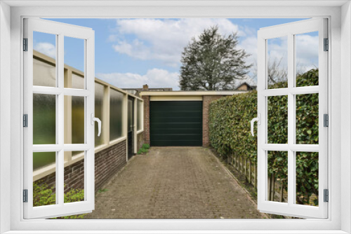 Fototapeta Naklejka Na Ścianę Okno 3D - a house in the netherlands, with a green garage door and brick driveway leading up to the home's entrance