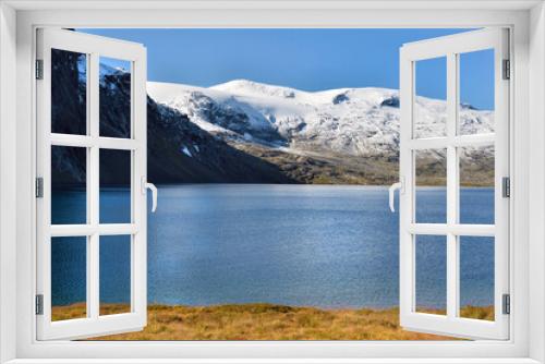 Fototapeta Naklejka Na Ścianę Okno 3D - beautiful norway landscape with blue lake nestled in the snow-capped mountains and surrounded by autum-coloured vegetation under blue sky
