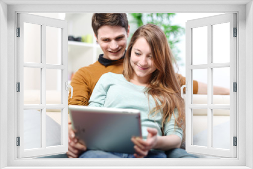 Young couple using digital tablet indoors on the sofa