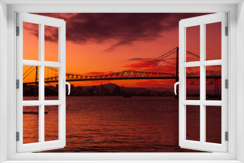 Fototapeta Naklejka Na Ścianę Okno 3D - Silhouette of cable bridge with sunset sky and reflection on water in Florianopolis, Brazil