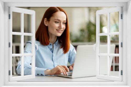 Smiling woman using laptop computer, working online sitting in modern office. Successful freelancer copywriter typing on keyboard, planning project. Happy student studying, online education