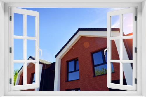 Fototapeta Naklejka Na Ścianę Okno 3D - New single family houses in a new development area. Residential homes with modern facade. Terraced family homes in newly developed housing estate. The real estate market in the suburbs.