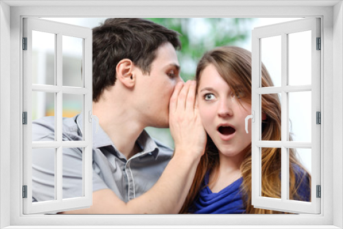 man whispering in the ear of his surprised wife