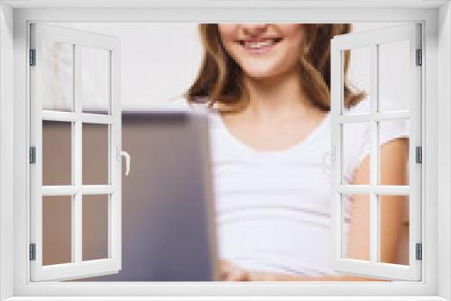 smiling teenage girl with laptop computer at home