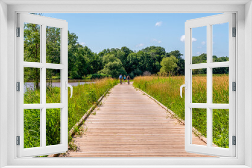 Fototapeta Naklejka Na Ścianę Okno 3D - Bicycle Riders On A Wooden Boardwalk Through the Marsh In Summer