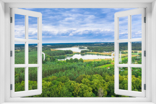 Fototapeta Naklejka Na Ścianę Okno 3D - Równina pokryta zielonym lasem. wśród gęstwiny drzew widać dwa jeziora. Niebo jest lekko zachmurzone. Zdjęcie z drona.