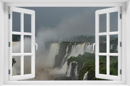 Fototapeta Naklejka Na Ścianę Okno 3D - Beautiful cascades of waterfalls collapse into a stormy river. Spray and fog rise into the sky. Green tropical vegetation on ledges. Iguazu Falls. Brazil.