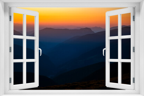 Fototapeta Naklejka Na Ścianę Okno 3D - Dark silhouettes of mountains at sunrise with an orange sky. Dark background with a copy space. The Parang Mountains, Romania.