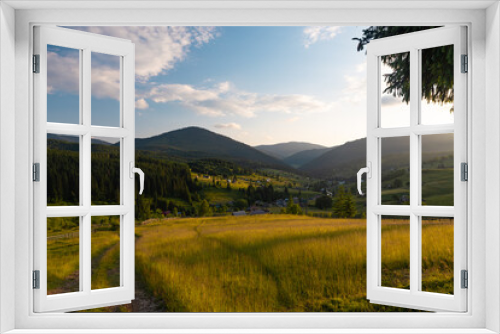 Fototapeta Naklejka Na Ścianę Okno 3D - A small village spread out on the hills among the coniferous forest